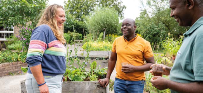 Drie mensen in gesprek in een gemeenschappelijke moestuin